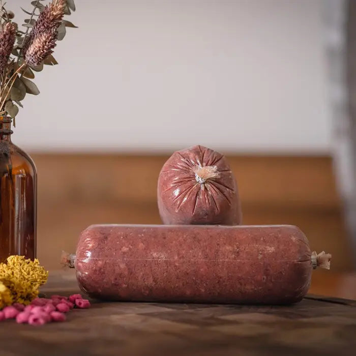 Two raw pork tubes on a wooden surface with a blurred background