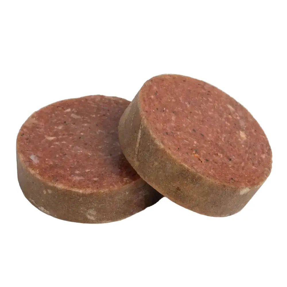 Two brown beef raw dog food patties on a white background